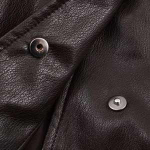 Macro shot of dark brown faux leather texture with silver metal snap button details