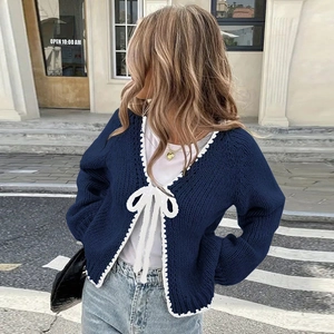 Detail of navy knit cardigan with white crochet lace edges and bow tie front closure