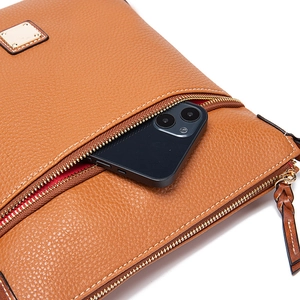 Detailed close-up of brown pebbled leather bag with exterior zipper and contrast stitching