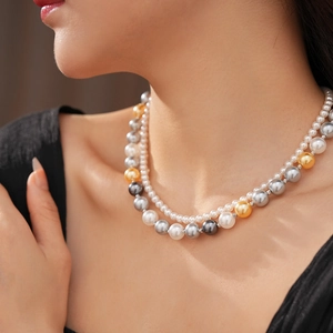 Gros plan d'un collier de perles à double rangée blanc et gris sur le cou d'un modèle