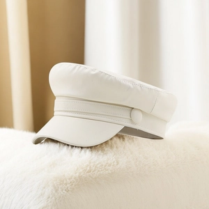 Detail shot of a cream white PU leather newsboy cap on a soft plush white texture