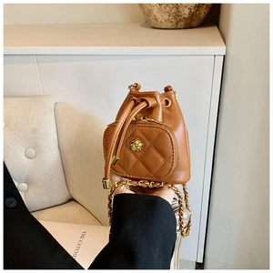 Detail of brown quilted mini bucket bag with gold flower charm and chain strap