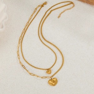 Double-layered golden stainless steel necklace featuring textured heart pendants on white surface