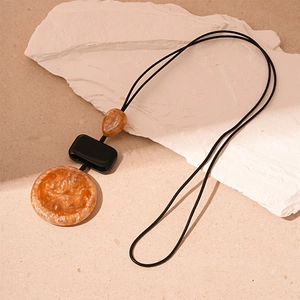 Minimalist resin sweater necklace with amber geometric pendants on a black cord