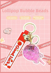 Macro detail of a pink lollipop keychain with quicksand stars and red Good Luck strap