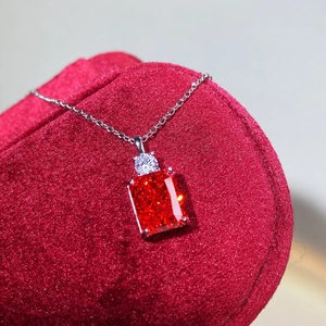 Macro shot of rectangular red gemstone pendant with small round diamonds on red velvet