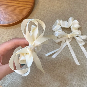 Détail d'un chouchou en satin blanc crème avec de longs rubans et une texture de soie