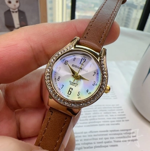 Close-up of a women's quartz watch with a brown leather strap and rhinestone gold bezel