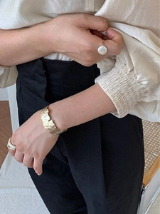 Vue détaillée d'une manchette dorée martelée et d'une bague perle baroque sur un mannequin
