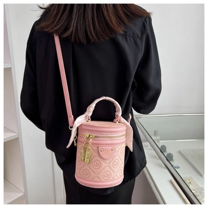 Detail of pink cylinder handbag with DM embossed pattern and decorative handle scarf