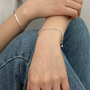 Close-up of minimalist S925 sterling silver bangle and interlocking link heart bracelet