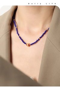 Detail of beaded necklace with navy blue faceted stones and a gold textured charm