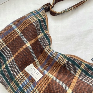 Macro detail of retro plaid crossbody bag in thick tweed fabric with cotton label tag