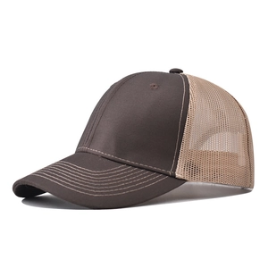 Detail view of brown trucker hat with mesh back and curved brim stitching on white background
