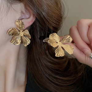 Detailed close-up of gold petal earrings showing textured metal finish on a model