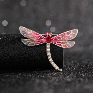Macro detail of golden dragonfly brooch with glitter gradient enamel and rhinestones