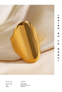 Macro d'une large bague en acier inoxydable doré poli sur soie beige luxueuse