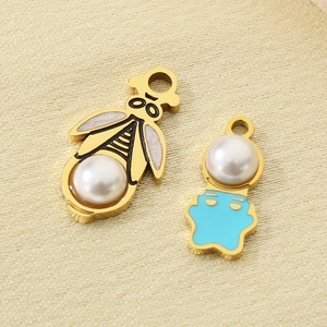 Macro shot of gold bee and blue bear jewelry pendants with elegant faux pearls