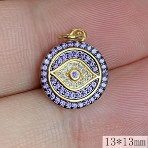 Macro view of a 13mm round gold evil eye pendant with purple and white zircon stones
