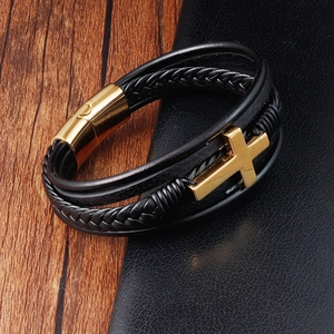 Macro detail of men's black braided leather bracelet with golden cross and magnetic clasp