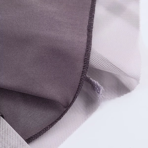 Macro detail of purple plaid fabric and grey mesh stitching on a long sleeve dress