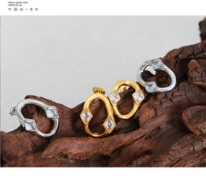 Macro detail of geometric gold and silver earrings with square cubic zirconia on wood