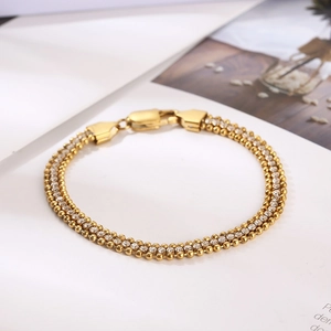 Dettaglio macro di un bracciale a tre file in oro con zirconi brillanti e chiusura a moschettone
