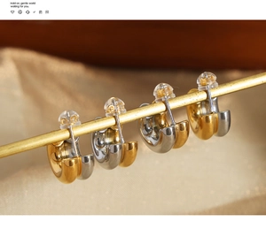 Detail of two-tone C-shaped hoop earrings with gold and silver finish on silk