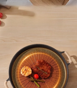 Macro view of maifan stone grill pan with hemp rope handles showing steak and vegetables