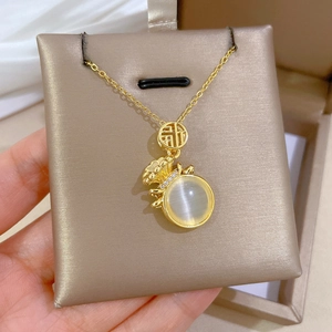 Détail du collier sac de chance avec pierre oeil de chat blanche et motif Fu