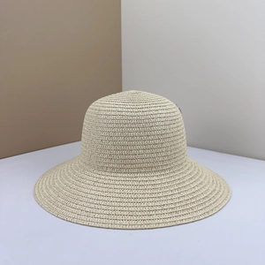 Dettaglio di un cappello di paglia intrecciato beige con corona rotonda e stile minimal