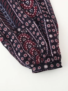 Close-up detail of paisley floral print on lightweight chiffon sleeve with ruffled cuffs