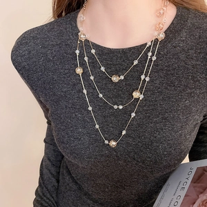 Close-up of elegant triple-layered gold necklace with clear and amber crystal beads on model