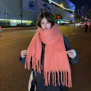 Detail of coral pink mohair scarf with soft fringe edges worn by a model in city street