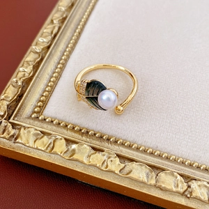 Detail of vintage gold ring with pearl and diamond-encrusted leaf on velvet