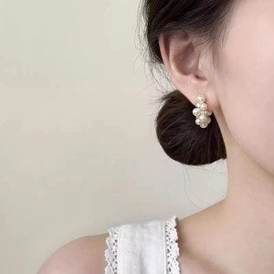 Elegant C-shaped pearl earrings with gold metal and crystals shown on a female model