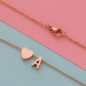 Macro detail of rose gold heart and letter A pendants with lobster clasp jewelry