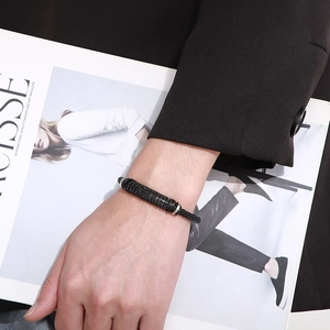 Gros plan d'un bracelet en cuir noir tressé avec des perles en acier inoxydable texturé