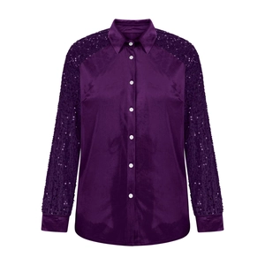 Detail of velvet blouse featuring sequined sleeves and elegant white pearl buttons