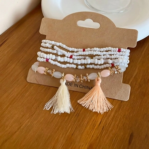 Detail of bohemian multilayer beaded bracelet set with decorative tassels and seed beads