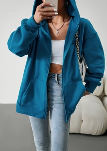 Detail of loose blue zip-up hoodie featuring fleece material and practical side pockets