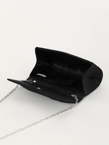 Macro view of black glitter evening clutch showing interior lining and silver chain strap