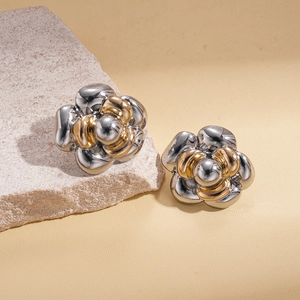 Close-up of metallic flower stud earrings with gold and silver two-tone petal design