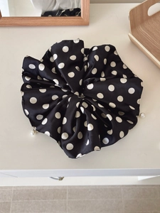 Close-up of black and white polka dot satin scrunchie with a delicate pearl pendant