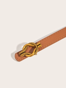 Detail of a slim brown leather belt featuring a golden knot-shaped metal buckle design