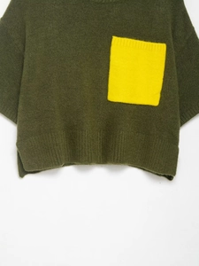 Détail du pull en tricot vert foncé avec poche contrastée jaune et ourlet côtelé doux
