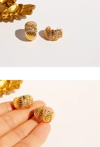 Detailed view of gold plated brass wide C-hoop earrings with textured twist and cubic zirconia