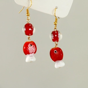 Macro shot of 3D red and white fish-shaped glass bead earrings on a card display