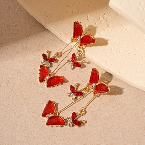 Detail view of red butterfly drop earrings with sparkling rhinestones on stone background