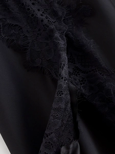 Dettaglio del pizzo nero cucito su tessuto di raso liscio con texture molto pregiate